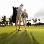 Father and son play golf in the early morning light