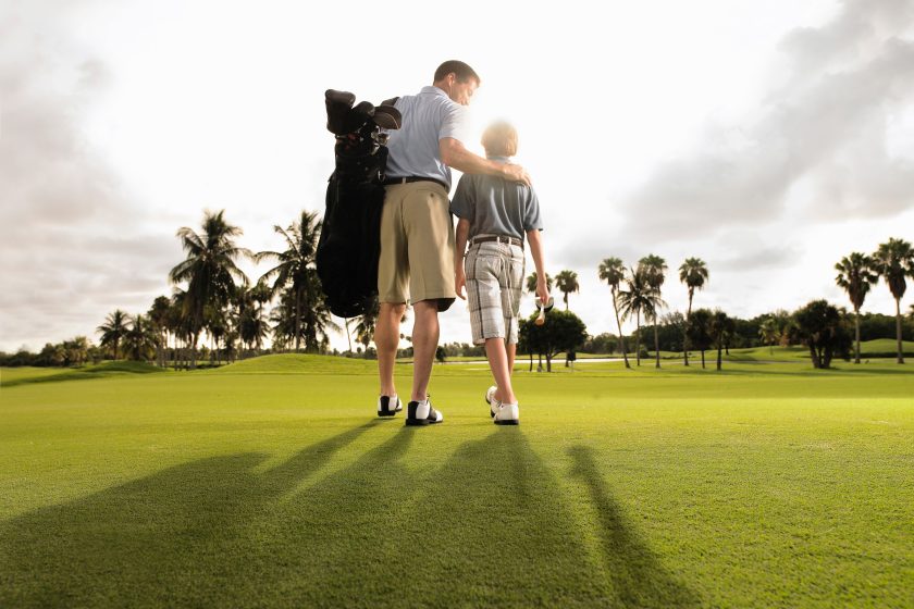 Father and son play golf in the early morning light